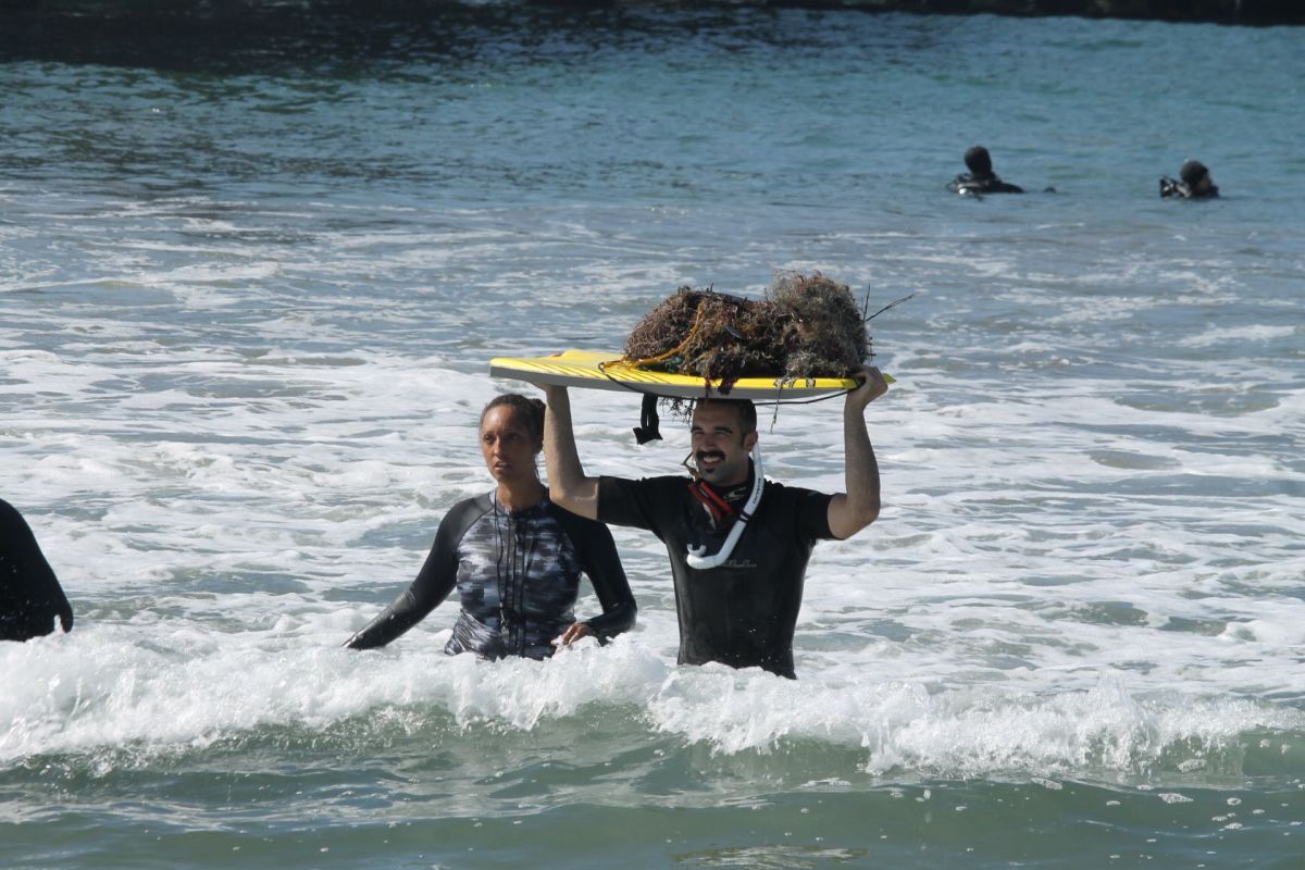 El buzo Ian Wells saca sobre una tabla de surf una red de pescar enredada con algas y desperdicios. / fotos: Jorge Luis Macías.