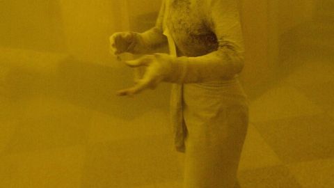 Empleada cubierta de polvo huye del WTC, 2001.