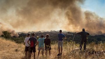 Un grupo de vecinos observa incendio en la localidad de Cualedro, en España.