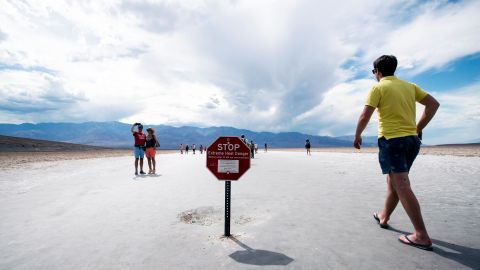 Visitantes cerca del aviso con la advertencia de calor extremo en el Valle de la Muerte.