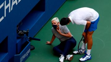 Novak Djokovic de Serbia (R) intenta ayudar a un juez de línea tras golpearla con un balón en la garganta durante su partido contra Pablo Carreño Buasta.