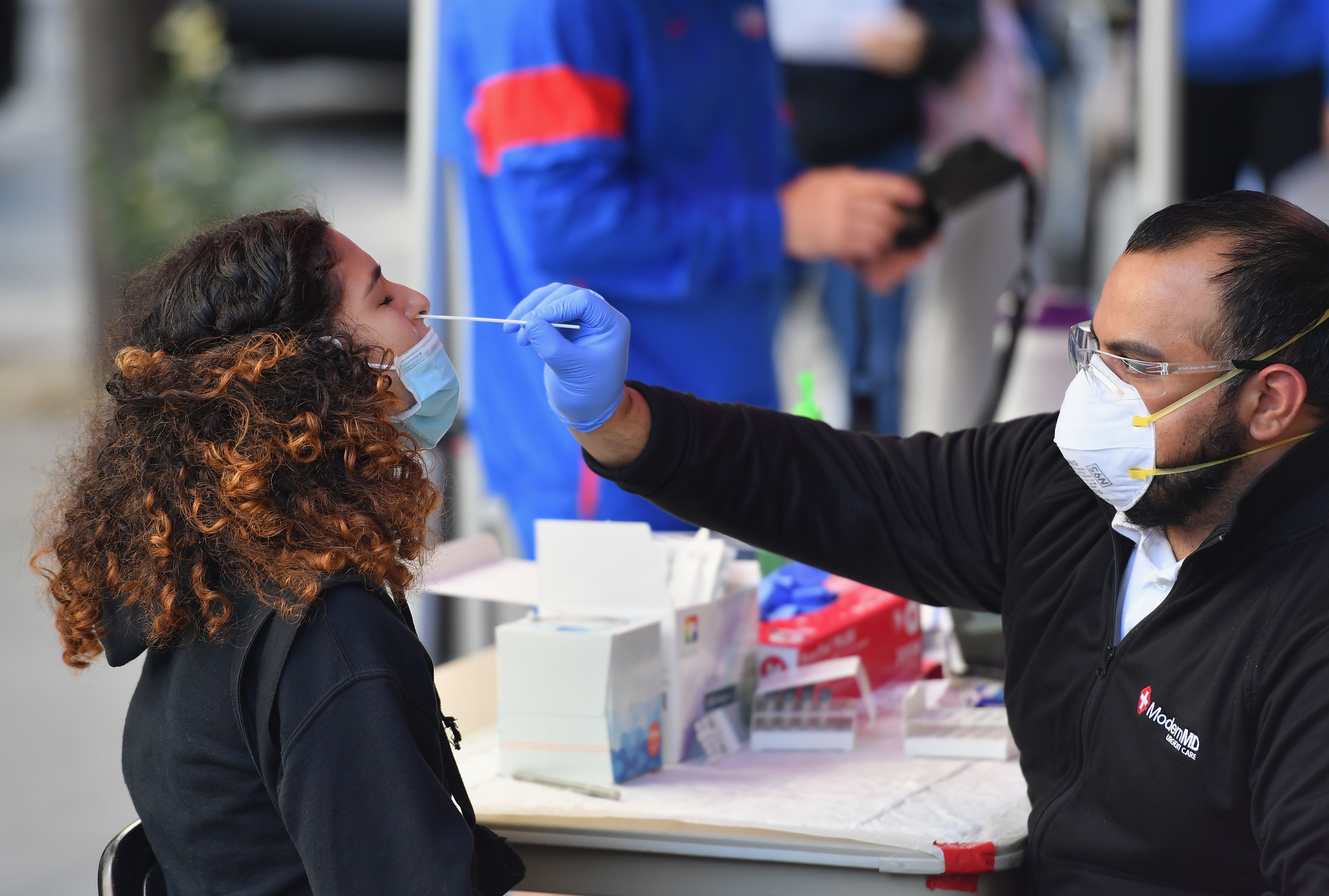 Un sanitario toma una muestra nasal pra el examen PCR a una estudiante en Nueva York.