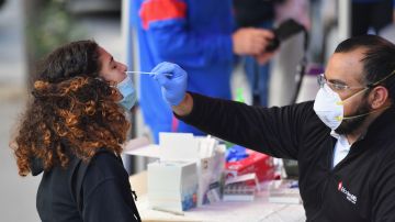 Un sanitario toma una muestra nasal pra el examen PCR a una estudiante en Nueva York.