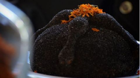 Pan de muerto con cobertura negra y relleno de camote morado.