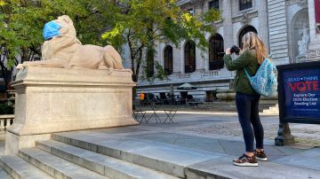 Una mujer retrata una escultura con mascarilla en Nueva York.