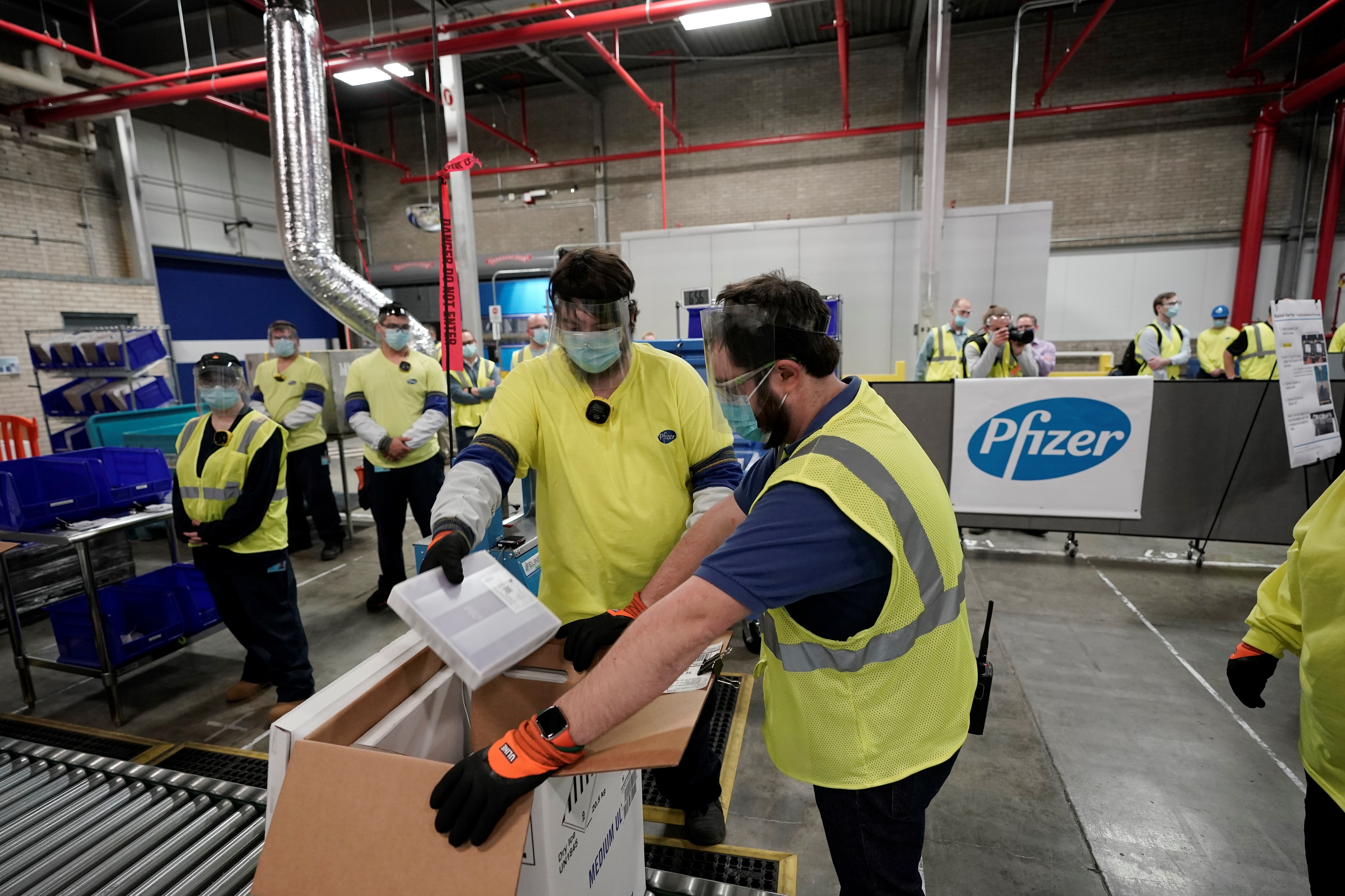 Trabajadores en la planta de Pfizer empacan la vacuna.