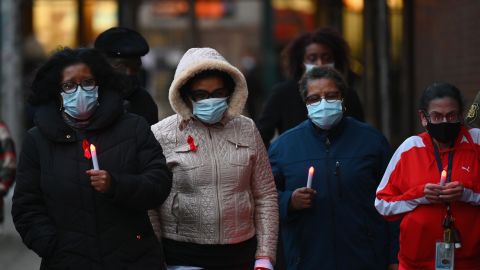 Mujeres sostienen el martes velas en conmemoración del Día Mundial del Sida y las muertes por COVID-19 en el NYC Health + Hospitals en Woodhull, en Brooklyn.
