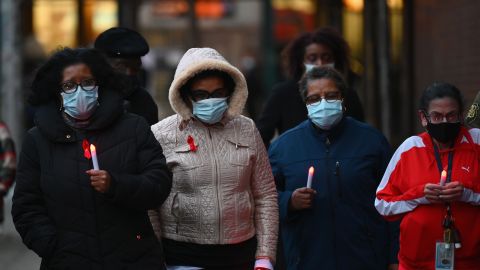 Mujeres sostienen el martes velas en conmemoración del Día Mundial del Sida y las muertes por COVID-19 en el NYC Health + Hospitals en Woodhull, en Brooklyn.