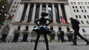 People walk past the New York Stock Exchange (NYSE) and 'Fearless Girl' statue at Wall Street on December 9, 2020 in New York City. (Photo by Angela Weiss / AFP) (Photo by ANGELA WEISS/AFP via Getty Images)