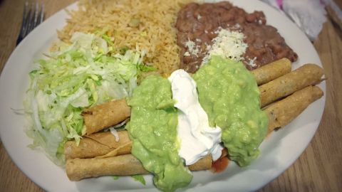 Flautas acompañadas de salsa de aguacate y crema.