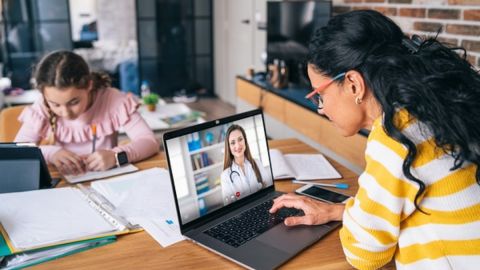 Mother trying to talk with doctor on laptop while staying at home. Homeschooling and distance learning, during COVID-19