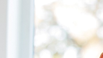 Diverse group of nurses, doctors, and other healthcare professionals are standing together confidently in a hospital hallway.