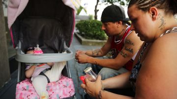 Una familia hispana desamparada sentada afuera de un refugio en Queens. La nueva ley busca que más personas dejen los albergues de la Ciudad.