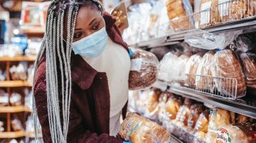Mujer comprando pan en supermercado