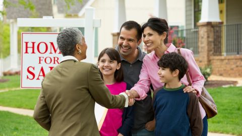 Family shaking hands with realtor at new house