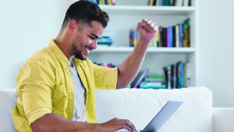 Happy latin american hipster man shopping online with computer indoor at home