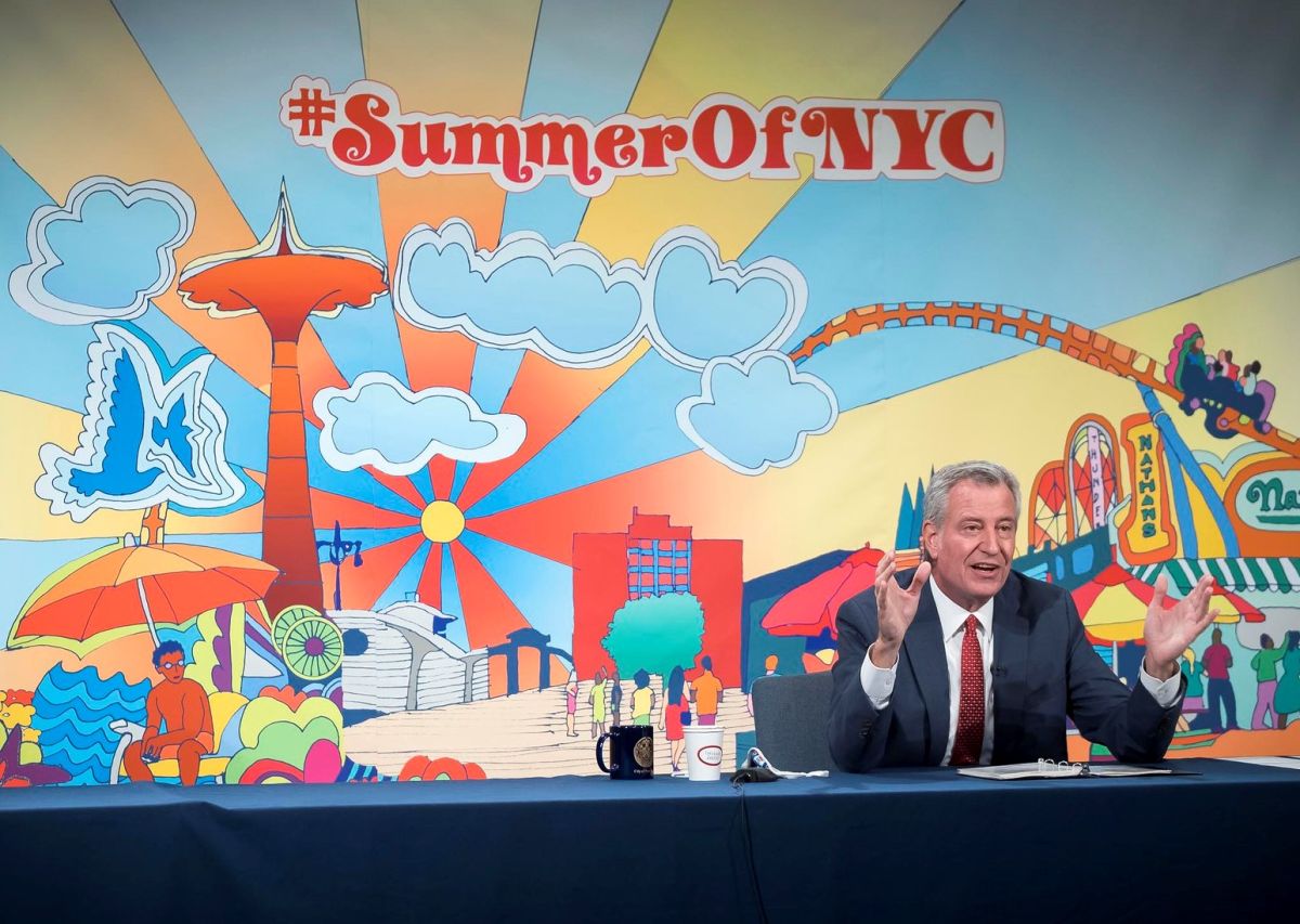 Mostrando una gran pancarta de #SummerOfNYC, De Blasio celebró las nuevas cifras del coronavirus. 