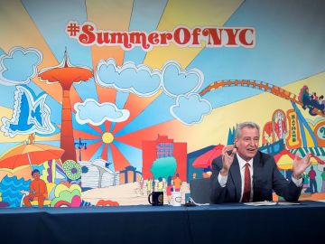 Mostrando una gran pancarta de #SummerOfNYC, De Blasio celebró las nuevas cifras del coronavirus.