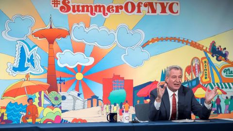 Mostrando una gran pancarta de #SummerOfNYC, De Blasio celebró las nuevas cifras del coronavirus.