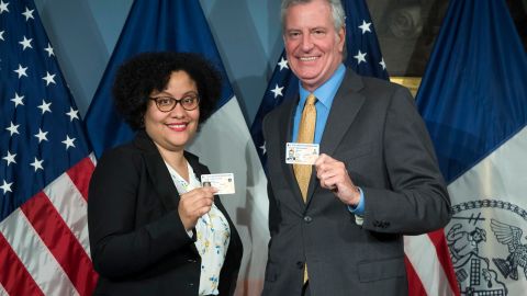 La comisionada de MOIA Raquel Batista y el alcalde De Blasio muestran sus IDNYC.