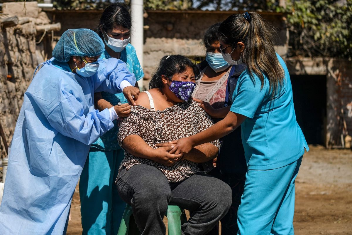 Trabajadores de la salud vacunan a una mujer en Arequipa, Perú, país donde surgió la variante Lambda de COVID.