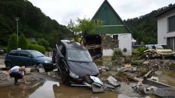 TOPSHOT - A resident kneels next to damaged cars and houses after heavy rain and floods in Hagen, western Germany, on July 15, 2021. - Heavy rains and floods lashing western Europe have killed at least 42 people in Germany and left many more missing, as rising waters led several houses to collapse. (Photo by INA FASSBENDER / AFP) (Photo by INA FASSBENDER/AFP via Getty Images)