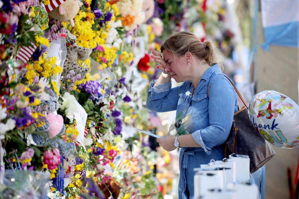Laura Solla llora mientras coloca flores en el sitio conmemorativo de las víctimas del colapso en Surfside.