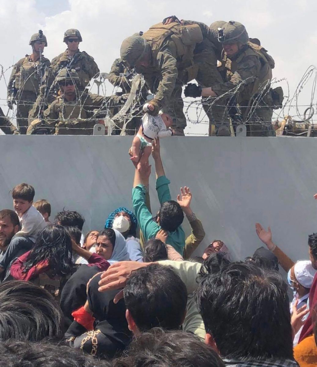 Marines estadounidenses pasan a una bebé por la valla del aeropuerto de Kabul como parte del proceso de evacuaciones en el país.