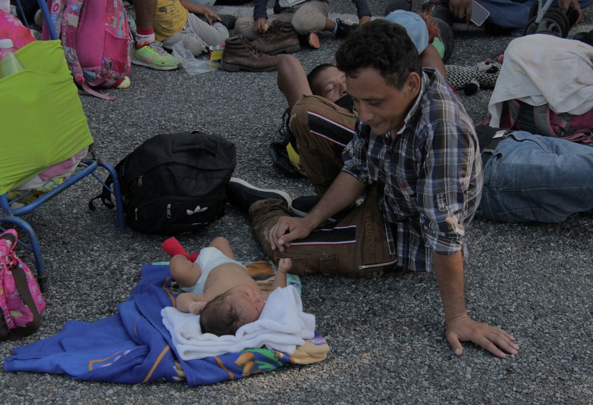 Un migrante centroamericano descansa junto a su bebé durante la caravana, en el municipio de Villa Comatitlán, estado de Chiapas (México).  