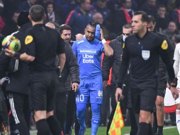Dimitri Payet saliendo escoltado del juego entre Marsella y Lyon tras ser agredido con una botella de agua.