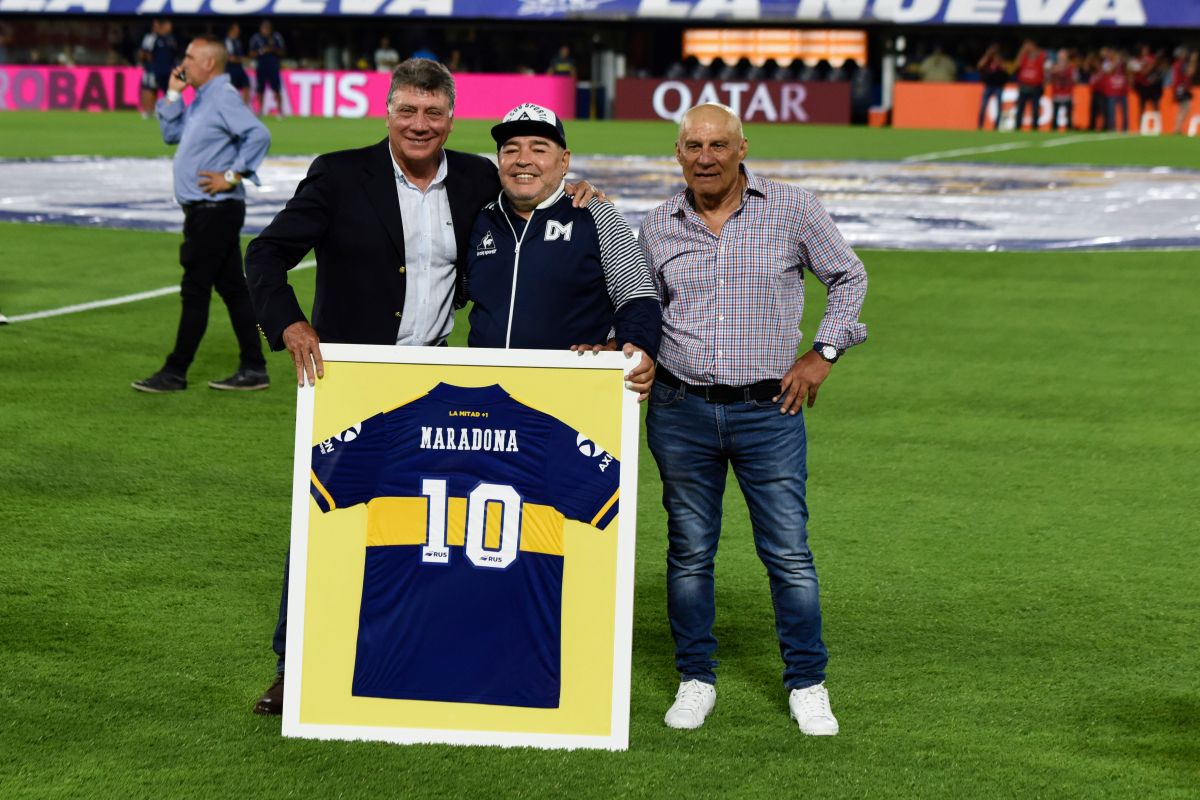Diego Maradona (medio) junto a Hugo Perotti (derecha) y Miguel Brindisi (izquierda) recibiendo su camisa enmarcada de Boca Juniors el 7 de marzo de 2020. 