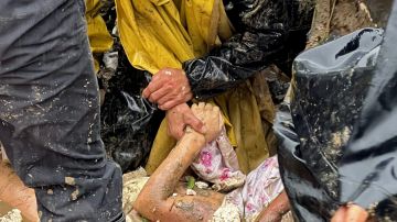 Un familiar sostiene la mano de una persona fallecida por un deslizamiento de tierra en Colombia.