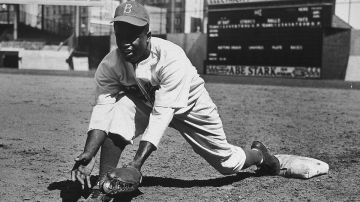 Jackie Robinson grounds ball at first base, 1950s.