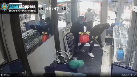 Cuatro ladrones saqueando las vitrinas de la joyería.