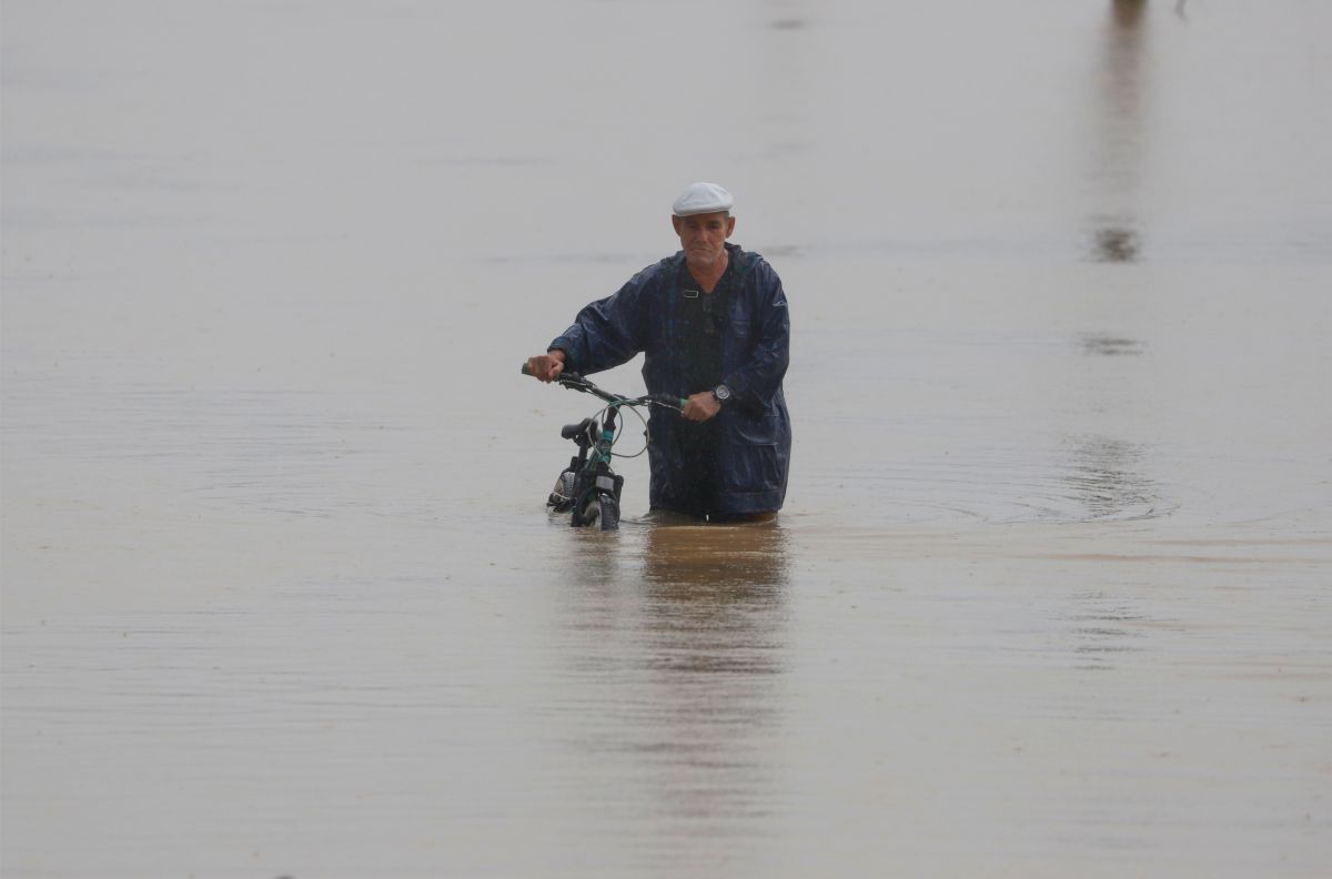Un hombre cruza con su bicicleta una calle inundada debido a lluvias por el paso del huracán Fiona, en Toa Baja, Puerto Rico.