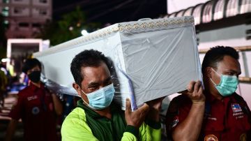 El personal de rescate lleva el ataúd de una víctima en la morgue del hospital en Udon Thani.