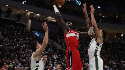 Montrezl Harrell (C) consigue una cesta ante la defensa de Giannis Antetokounmpo (R).