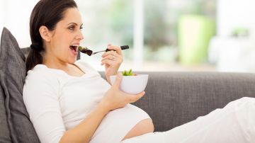 Mujer embarazada comiendo vegetales