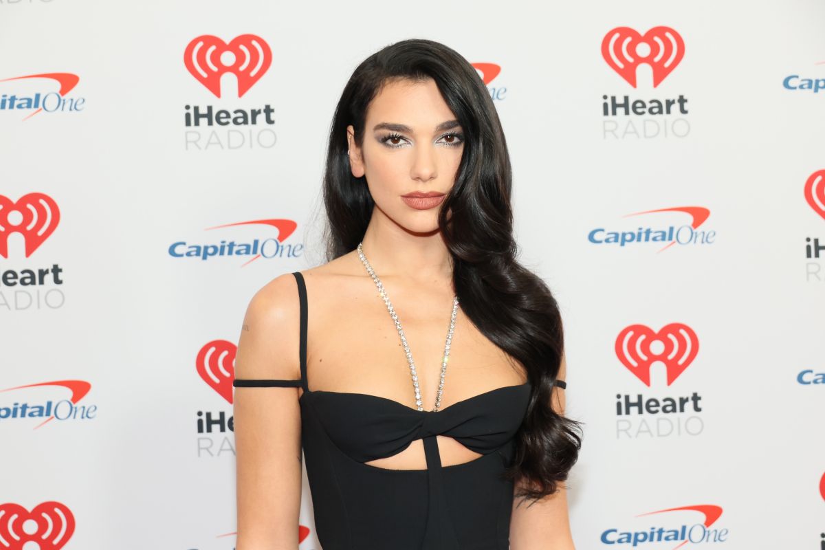 Dua Lipa wears a transparent jumpsuit with a neckline on her back that reveals her lingerie