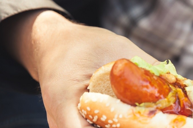 Adulto comiendo hot dog