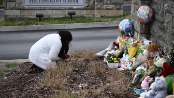 Una mujer presenta sus respetos en un memorial improvisado para las víctimas fuera del edificio de la Escuela Covenant.