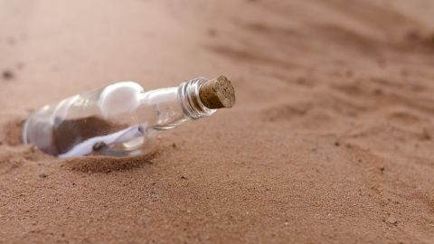 Botella de vino con una nota en una playa