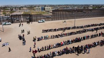 Un grupo de inmigrantes formados en la frontera de México y Estados Unidos.
