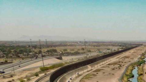 Fotografía aérea muestra a cientos de migrantes mientras esperan por papeles junto al muro fronterizo en El Paso, Texas