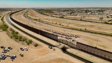 Fotografía aérea muestra a cientos de migrantes mientras esperan por papeles junto al muro fronterizo en El Paso, Texas
