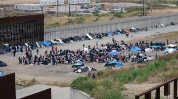 Inmigrantes permanecen en un campamento junto al muro fronterizo el 12 de mayo de 2023, en la ciudad de Tijuana, México.