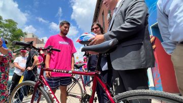 El migrante Anderson Villacres recibiendo su bicicleta del Comisionado Manuel Castro