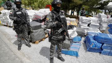 Un grupo de agentes de la Policía Nacional de Ecuador custodia varias bolsas con bloques de cocaína para ser destruidos.