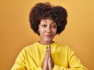 Young,African,American,Woman,Standing,Over,Yellow,Background,Praying,With