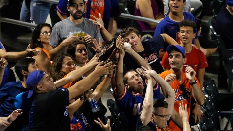 Fanáticos de Mets intentan atrapar una pelota en un encuentro ante Atlanta Brves